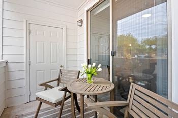 A small porch with a table and chairs and a sliding glass door